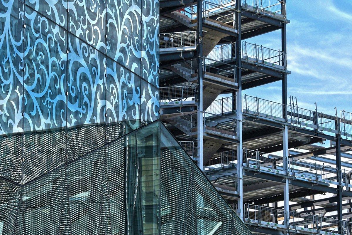 Patterned glass facade beside a steel staircase