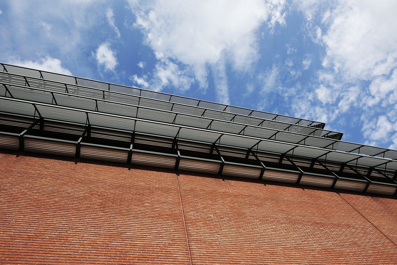 Brick wall and steel canopy under a cloudy sky