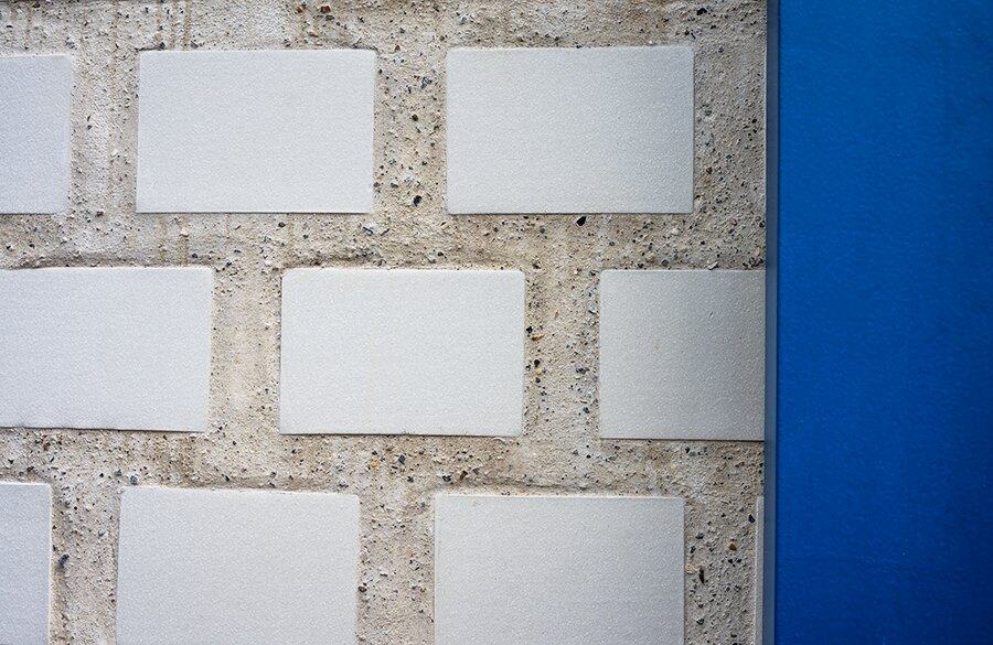 White tiles set in concrete beside a blue wall
